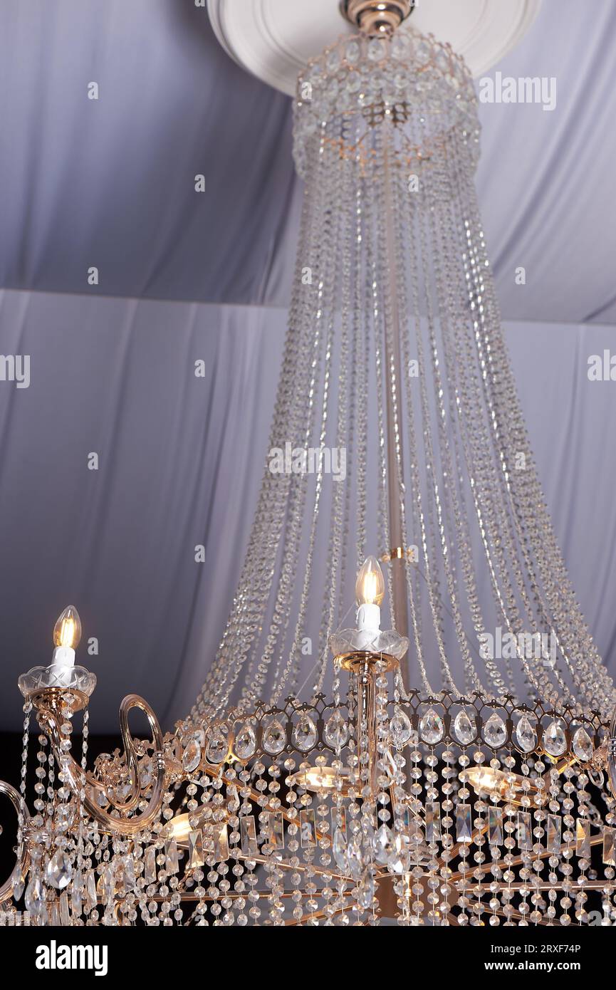 Schwerer Kristallleuchter mit einer Decke, die mit Stoffen verziert ist. Palace-Stil, Luxus Stockfoto