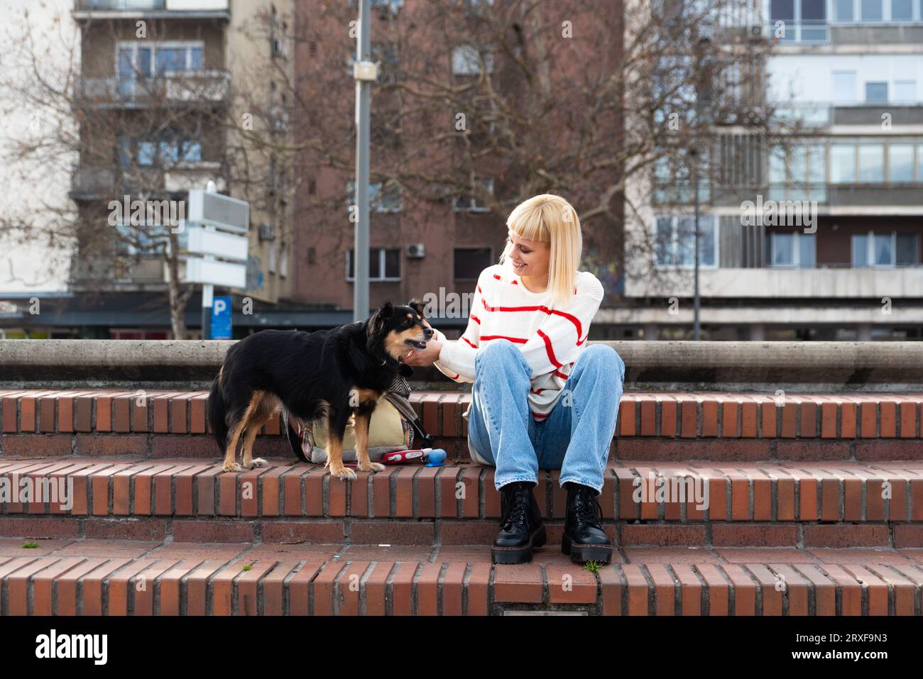 Junges Mädchen im Punk-Stil, das ihre Freizeit im Freien mit ihrem adoptierten und geretteten Hund aus Tierheimen verbringt und viel Zeit und Spaß hat Stockfoto