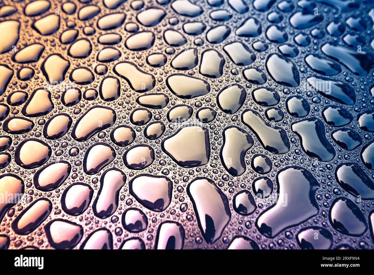 Abstrakte Darstellung von Regenwassertropfen auf schwarzer Metalloberfläche, Cross-Processing-Effekt angewendet Stockfoto