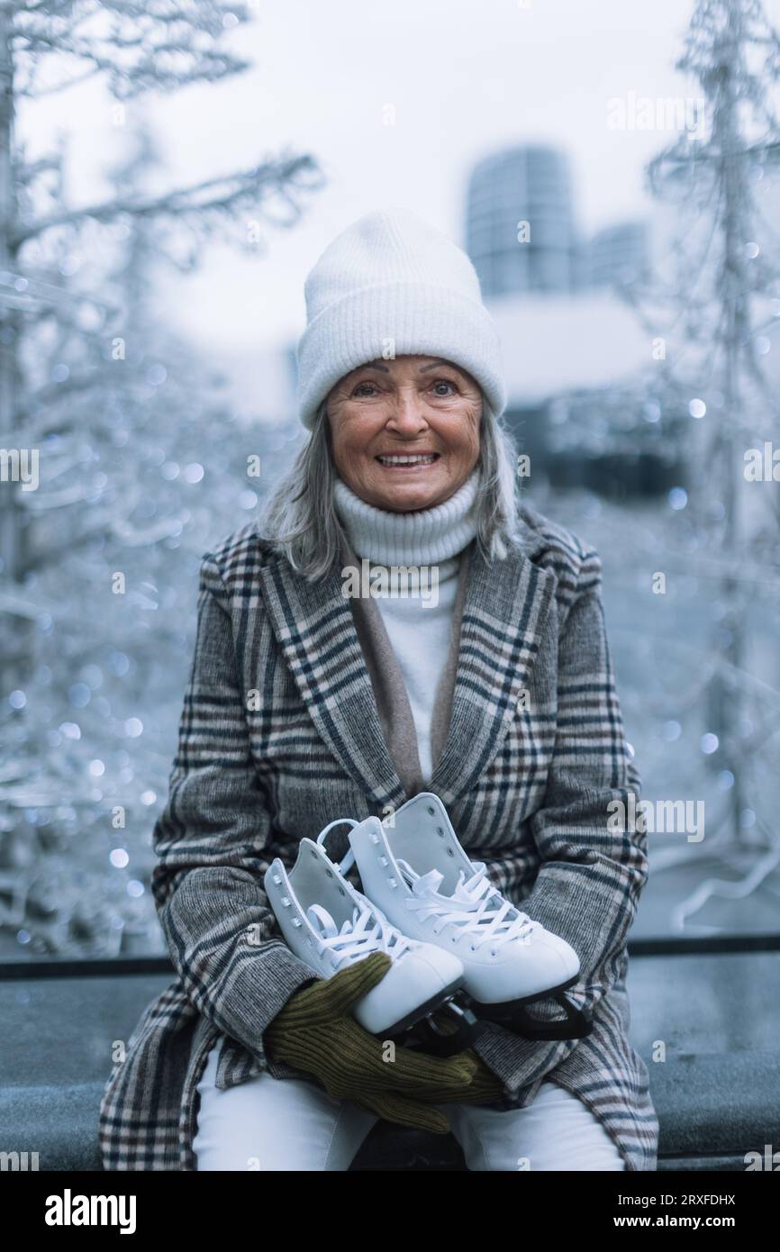 Porträt einer glücklichen Seniorin im Winter auf der Eislaufbahn im Freien. Stockfoto