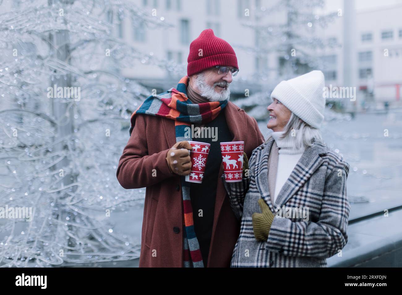 Glückliches Seniorenpaar genießt den weihnachtsmarkt, trinkt Glühwein. Stockfoto