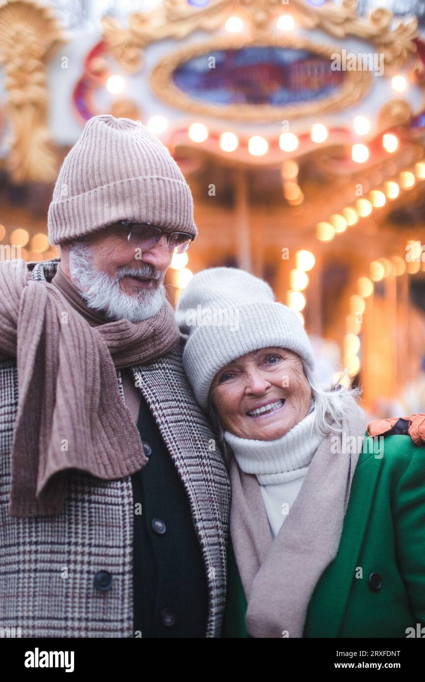 Glückliches Seniorenpaar genießt den weihnachtsmarkt, kauft Geschenke. Stockfoto