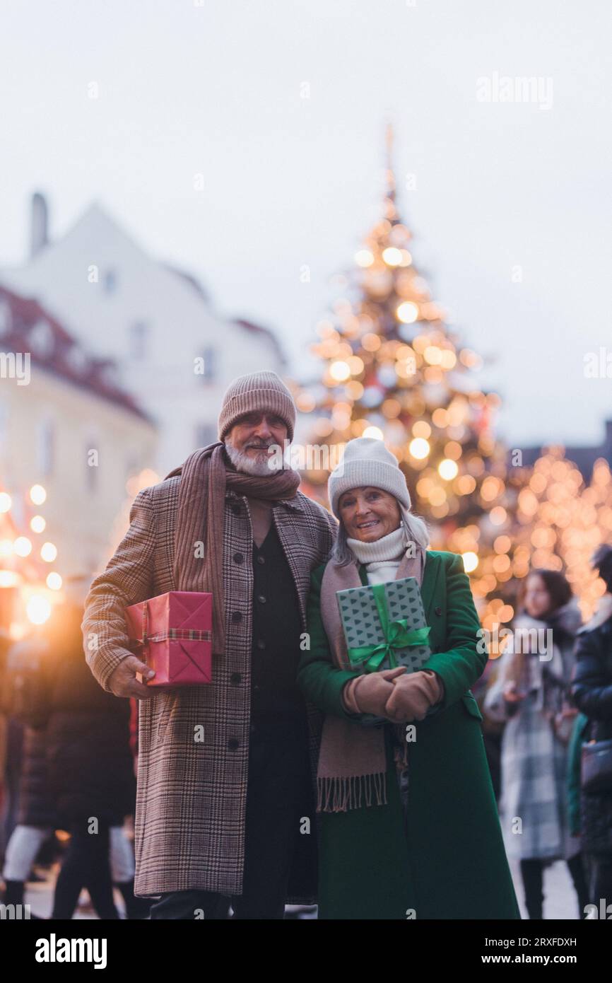 Glückliches Seniorenpaar, das weihnachtsmarkt in der Stadt genießt und Geschenke kauft. Stockfoto