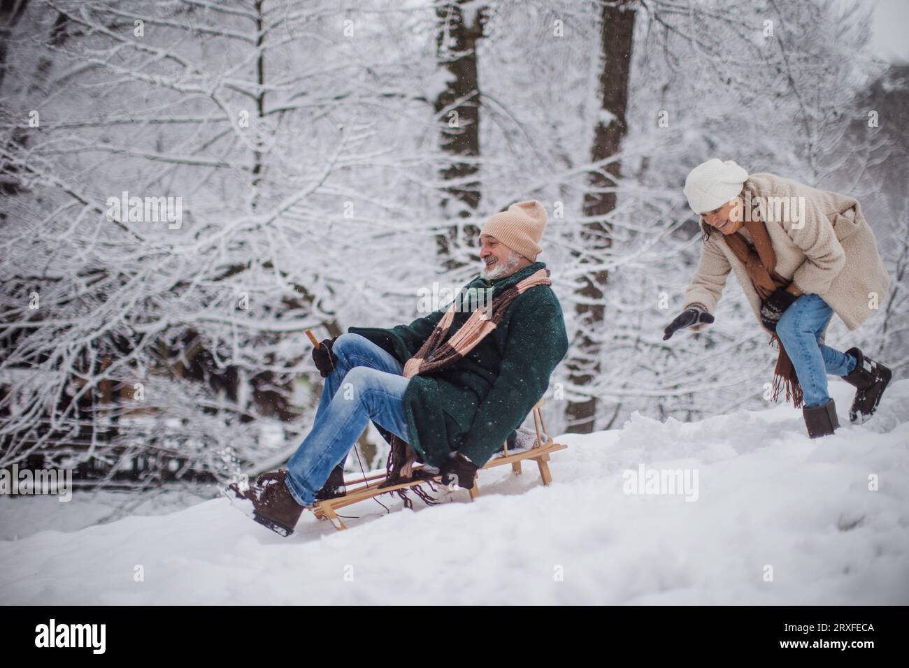 Seniorenpaar mit Spaß an kalten Wintertagen, Rodeln den Hügel hinunter. Stockfoto