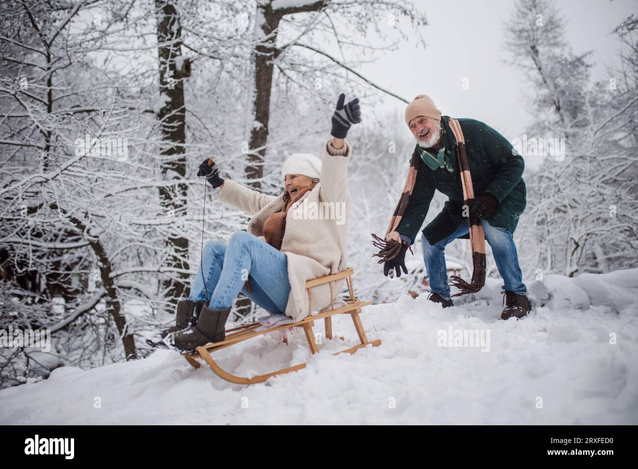 Seniorenpaar mit Spaß an kalten Wintertagen, Rodeln den Hügel hinunter. Stockfoto