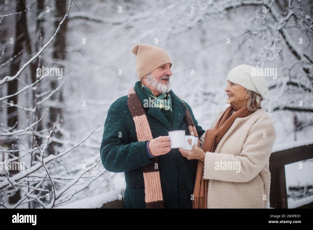 Elegantes Seniorenpaar mit heißem Tee im Freien, an kalten, schneebedeckten Wintertagen. Stockfoto