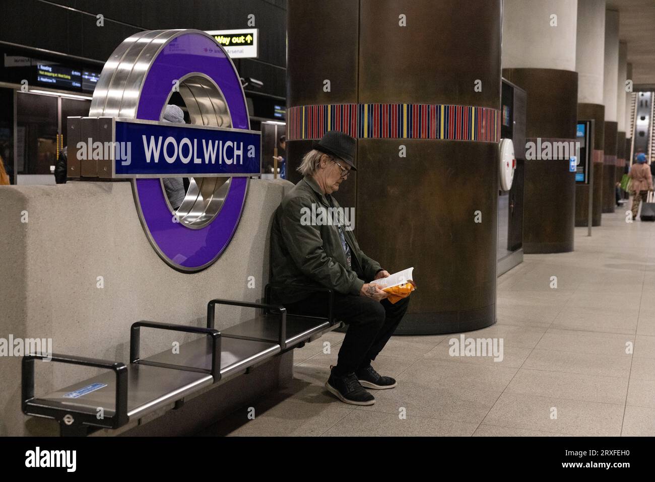 Mann, der sein Buch las, während er auf einen Zug an der Woolwich Elizabeth Line Station in East London, England, wartete Stockfoto