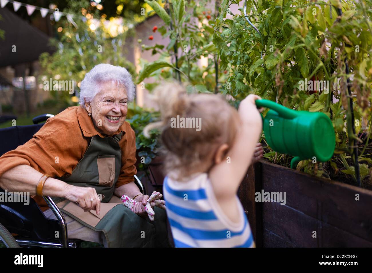 Porträt eines kleinen entzückenden Mädchens, das ihrer Großmutter im Garten hilft. Stockfoto