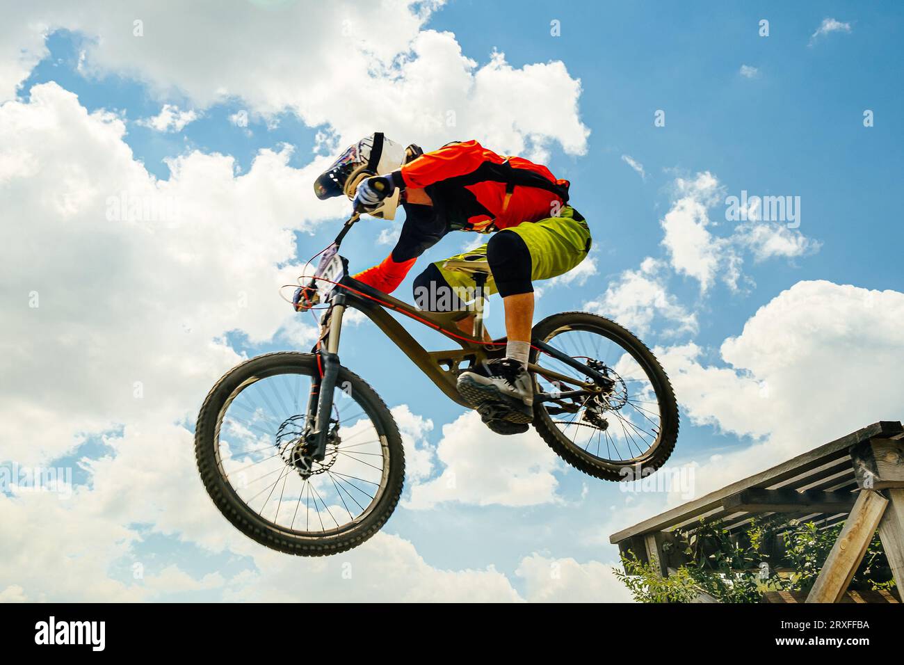 Man-Mountainbiker springen im Flug bergab. Vor dem Hintergrund des blauen Himmels Stockfoto