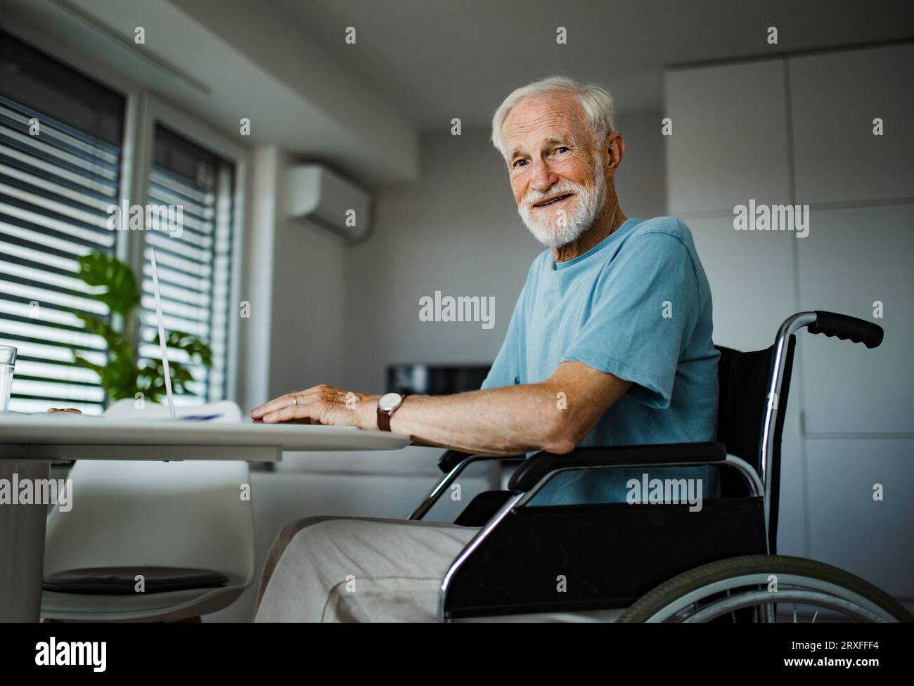 Älterer Mann im Rollstuhl, der im Ruhestand arbeitet. Stockfoto