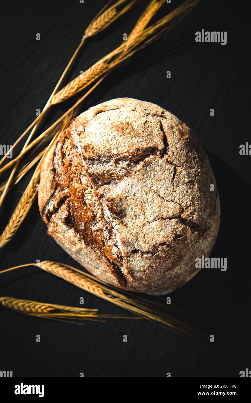 Frisch gebackenes traditionelles Brot auf einem schwarzen Brett. Hefe-freies Roggenbrot, Nahaufnahme. Lebensmittelhintergrund. Stockfoto