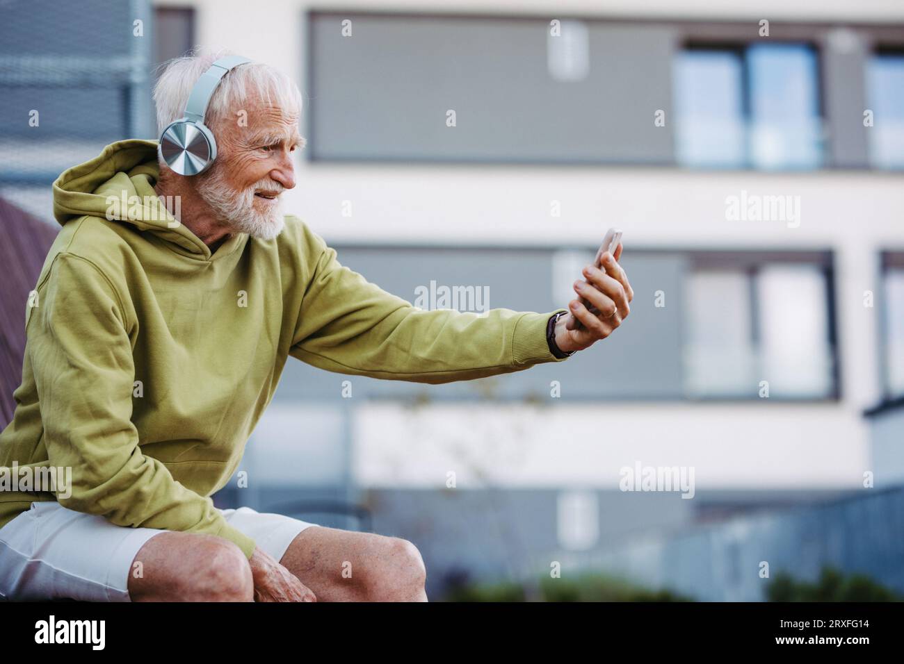 Älterer Mann, der Musik über kabellose Kopfhörer hört und sich auf seinen Morgenlauf vorbereitet. Stockfoto
