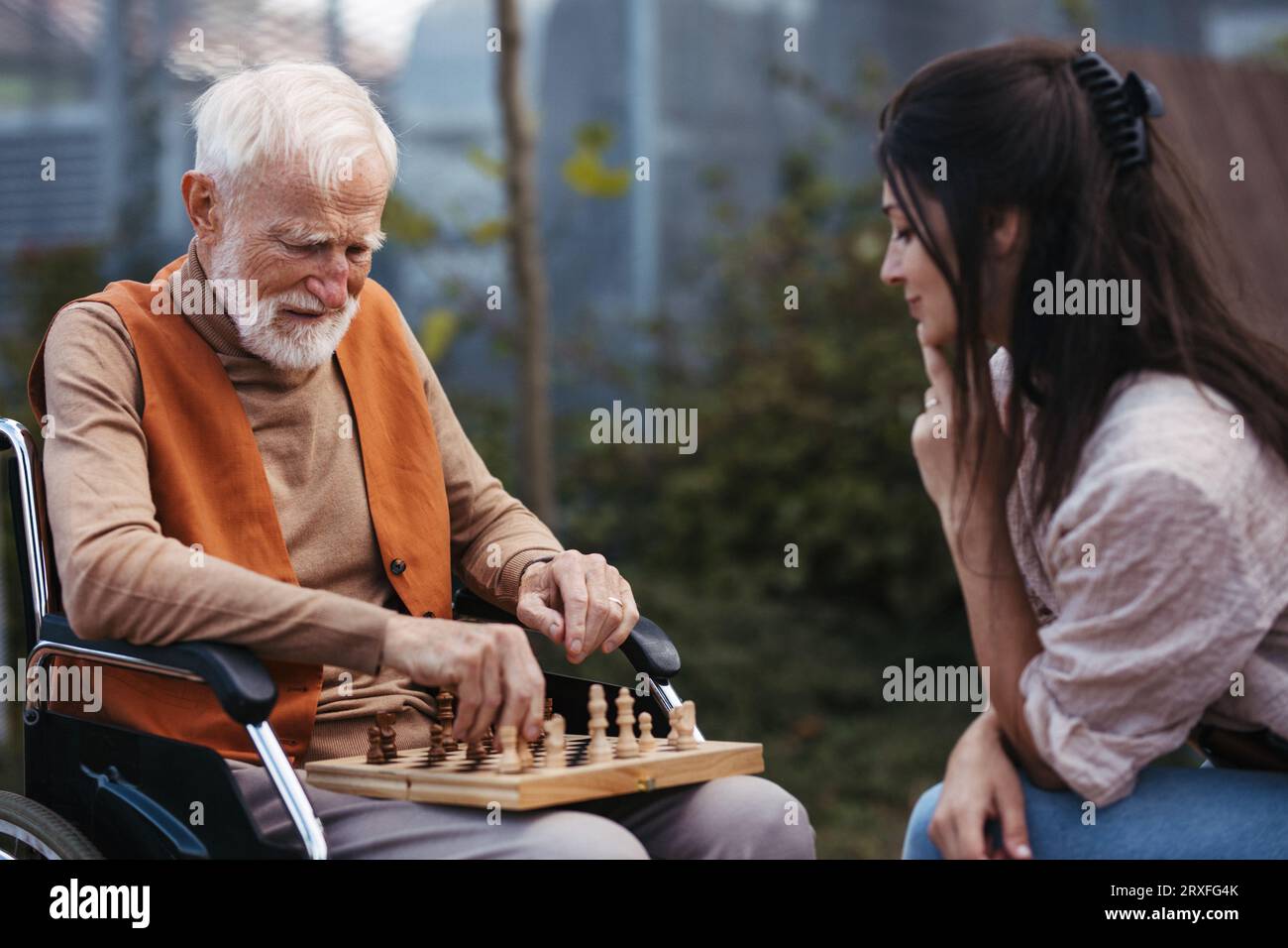 Älterer Mann, der mit seiner Tochter im Freien Schach spielt. Stockfoto