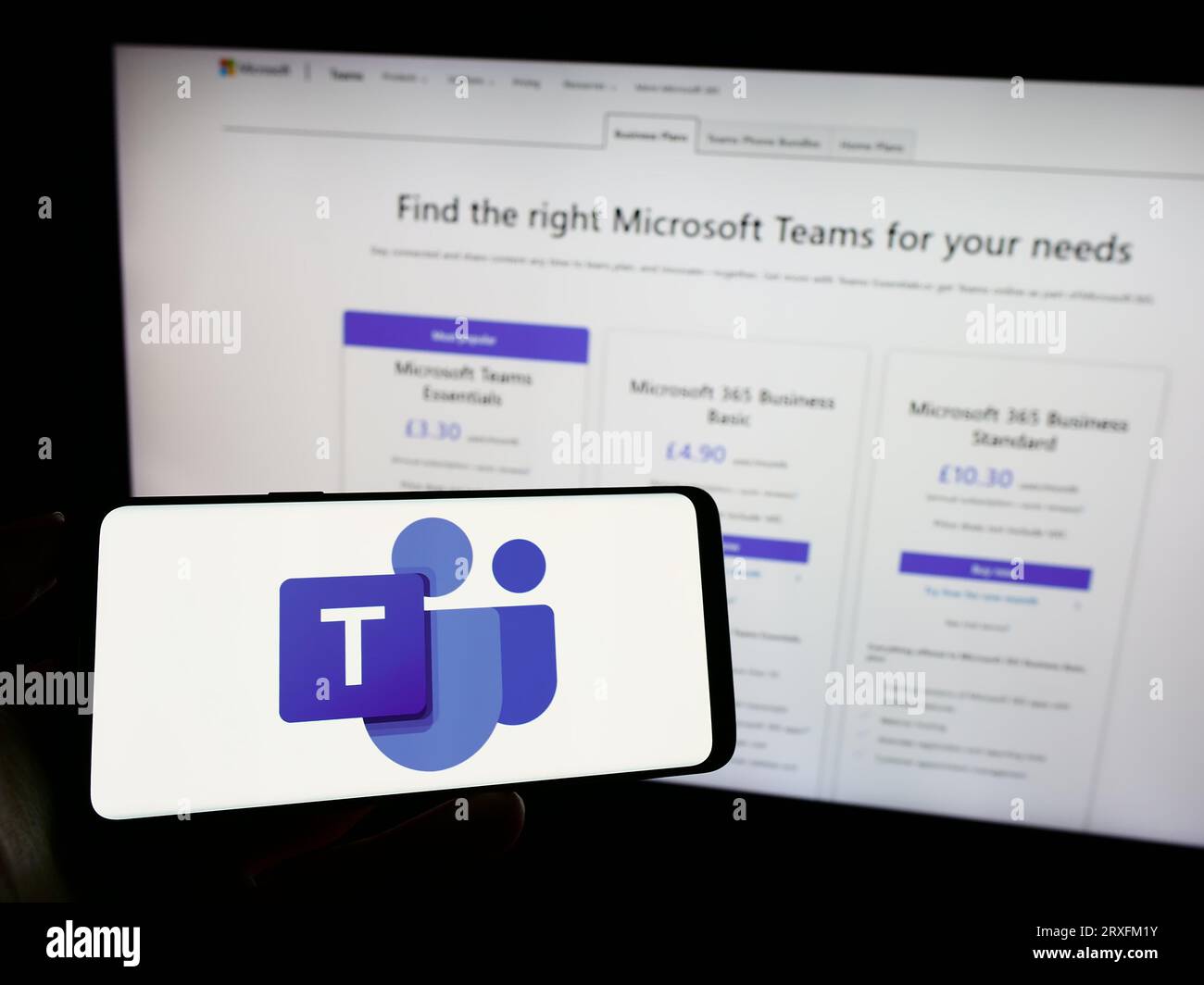 Person, die ein Mobiltelefon mit dem Logo der Business Communication Platform hält Microsoft Teams auf dem Bildschirm vor der Webseite. Konzentrieren Sie sich auf das Display des Telefons. Stockfoto