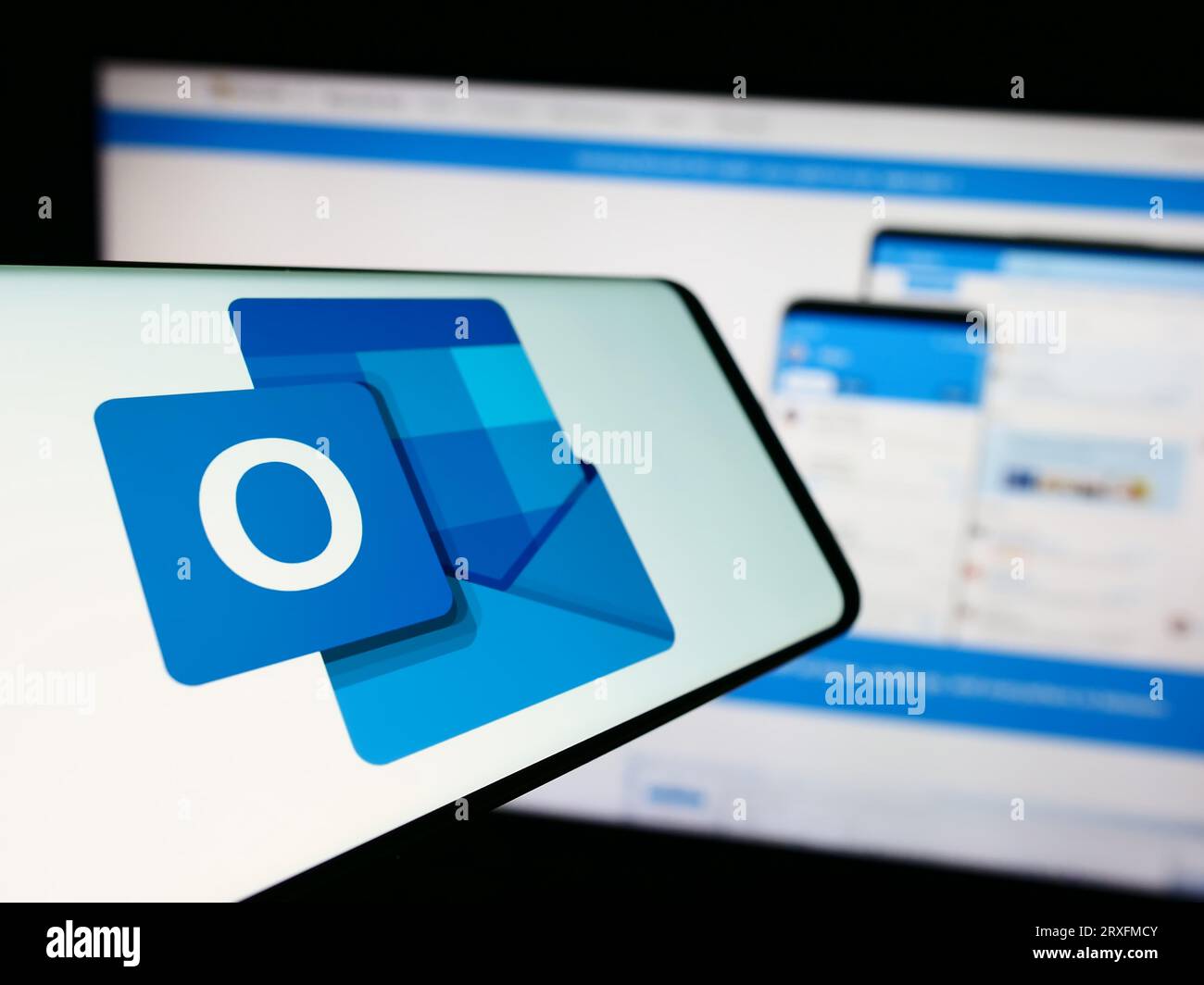 Mobiltelefon mit Logo der E-Mail-Software Microsoft Outlook auf dem Bildschirm vor der Unternehmenswebsite. Konzentrieren Sie sich auf die Mitte-links-Anzeige des Telefons. Stockfoto