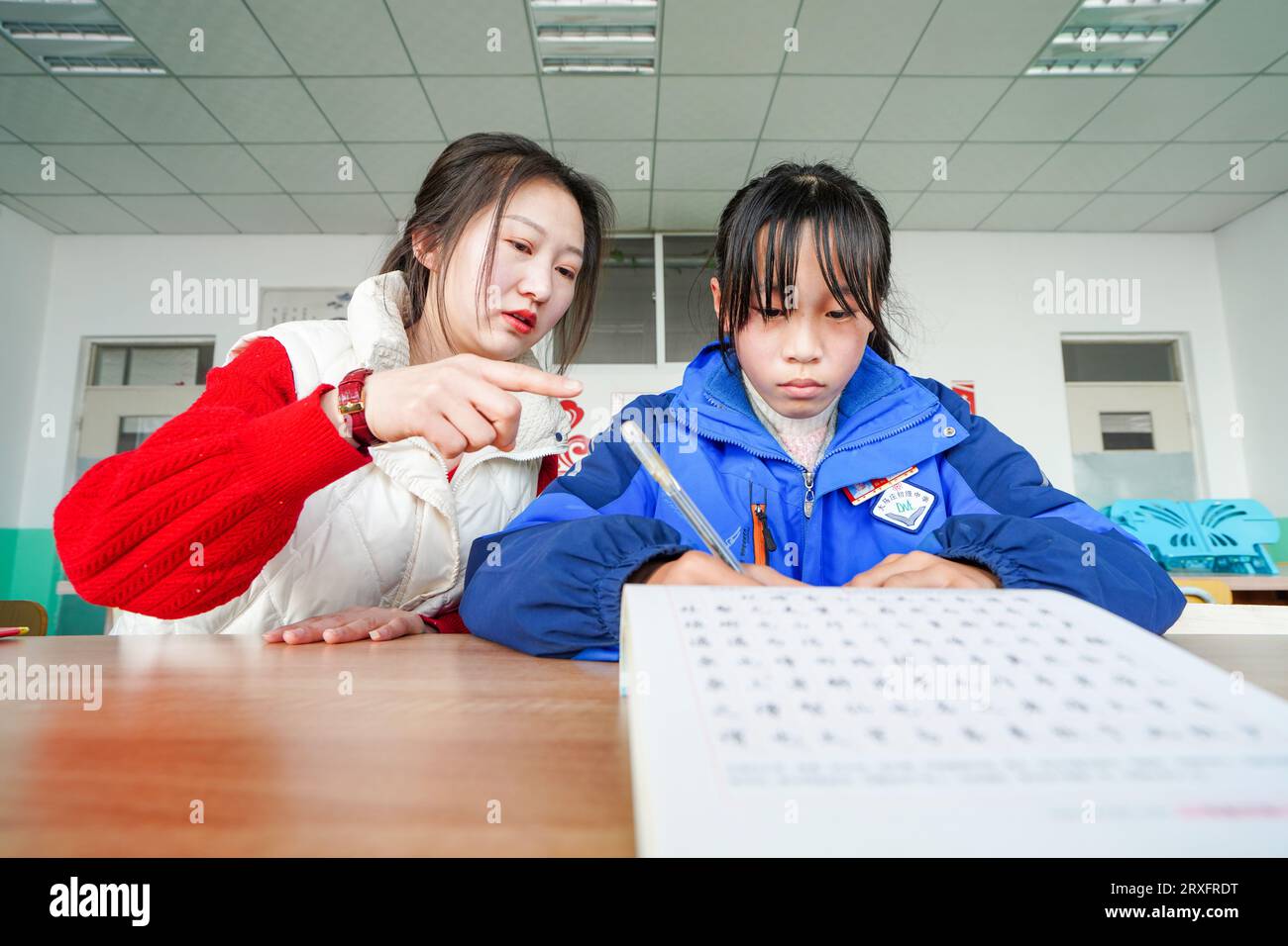 Luannan, China - 9. März 2023: Weibliche Lehrerin führt Schüler in der Praxis der Kalligraphie, Nordchina Stockfoto