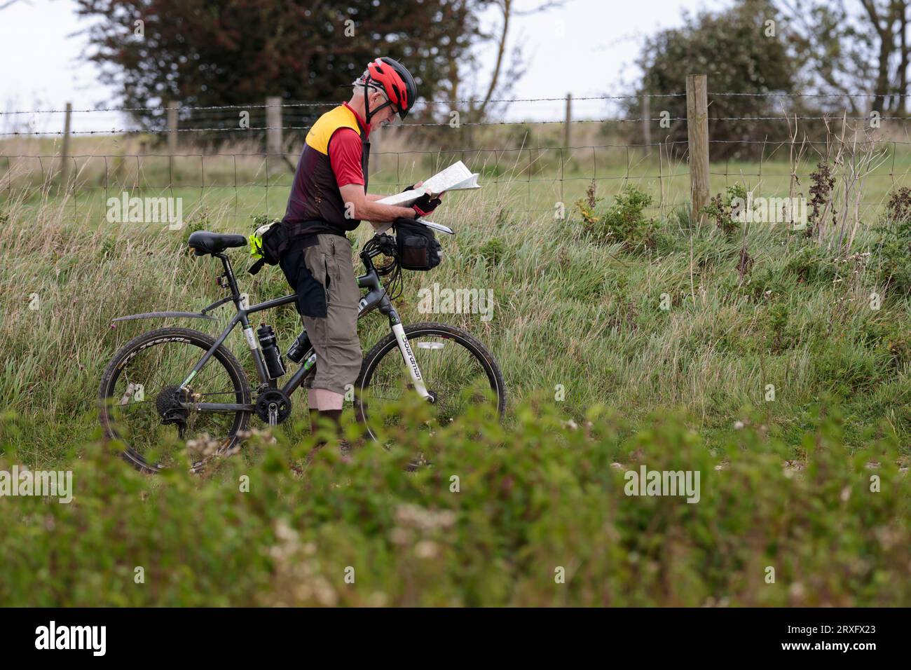 Radfahrer, die anhalten, um Karte zu lesen, schieben Fahrrad auf South Downs UK Gesundheit und Fitness mit schwarzen und roten Helm rot schwarz und gelb Oberteile Stockfoto