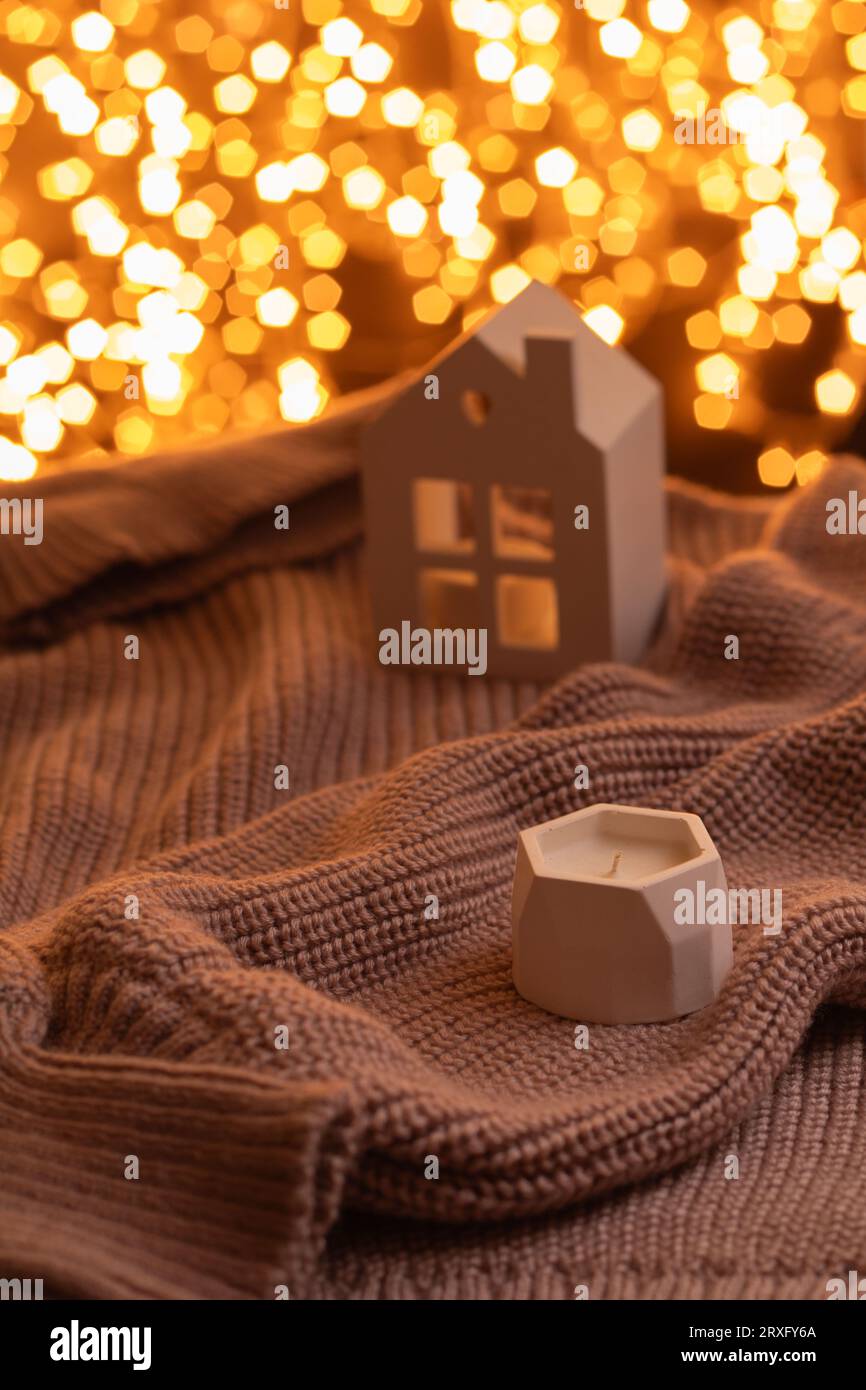 Foto gestrickter warmer Pullover kleine Kerze Weihnachtsgirlande Hintergrund Bokeh atmosphärisches Winterfoto Stockfoto