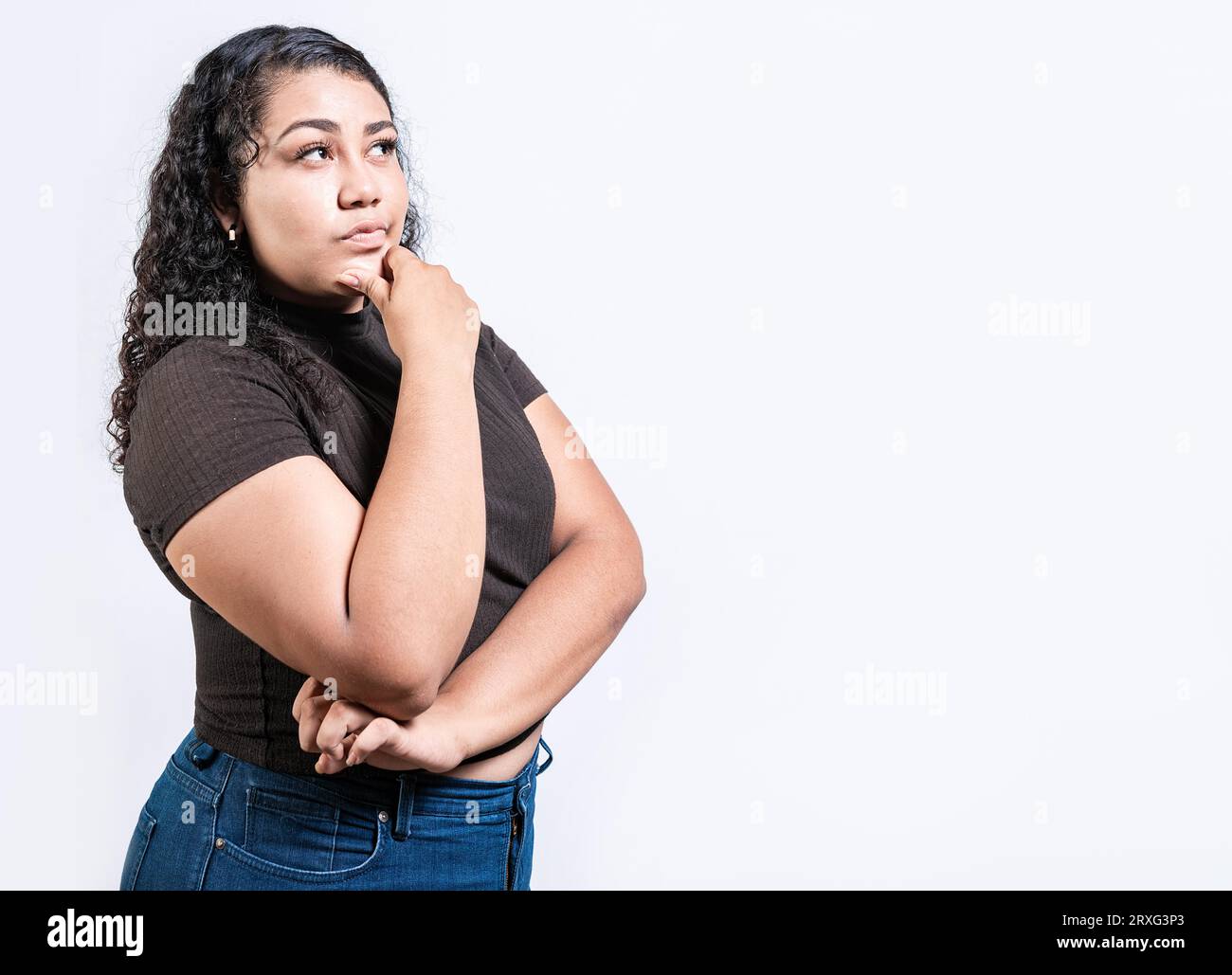 Nachdenkliche Menschen mit der Hand auf dem Kinn. Lateinisches Mädchen, das sich mit der Hand auf dem Kinn fragt Stockfoto