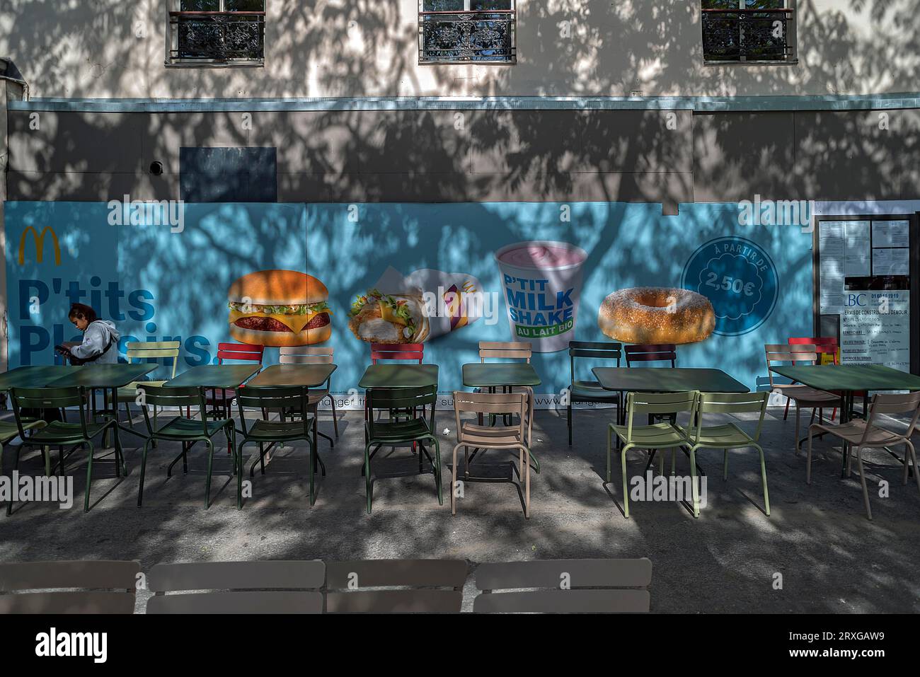 Poster mit Werbung für ein Fast-Food-Restaurant, Tische und Stühle davor, Paris, Frankreich Stockfoto