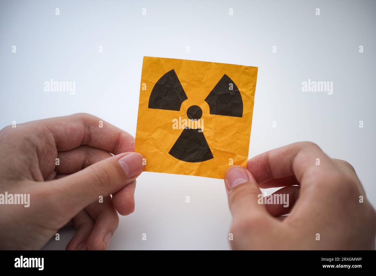 Ein junger Mann, der ein Strahlungswarnschild in den Händen hält. Nahaufnahme. Stockfoto