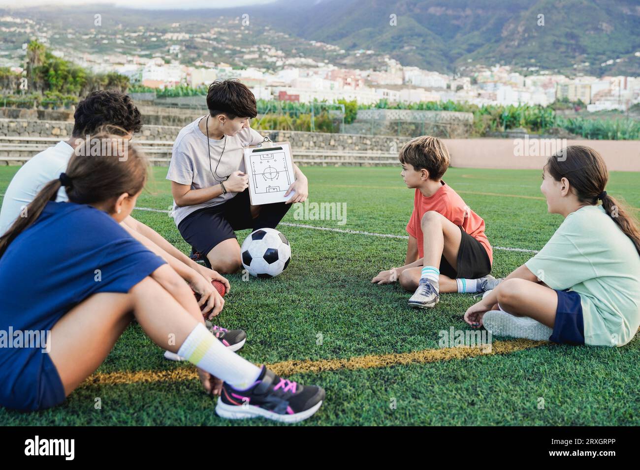 Fußballtrainerin, die Kinder auf dem Fußballfeld trainiert - Trainer, die Taktik und Strategiespiele an Bord unterrichten - Konzept für Kinder und Sportleben Stockfoto