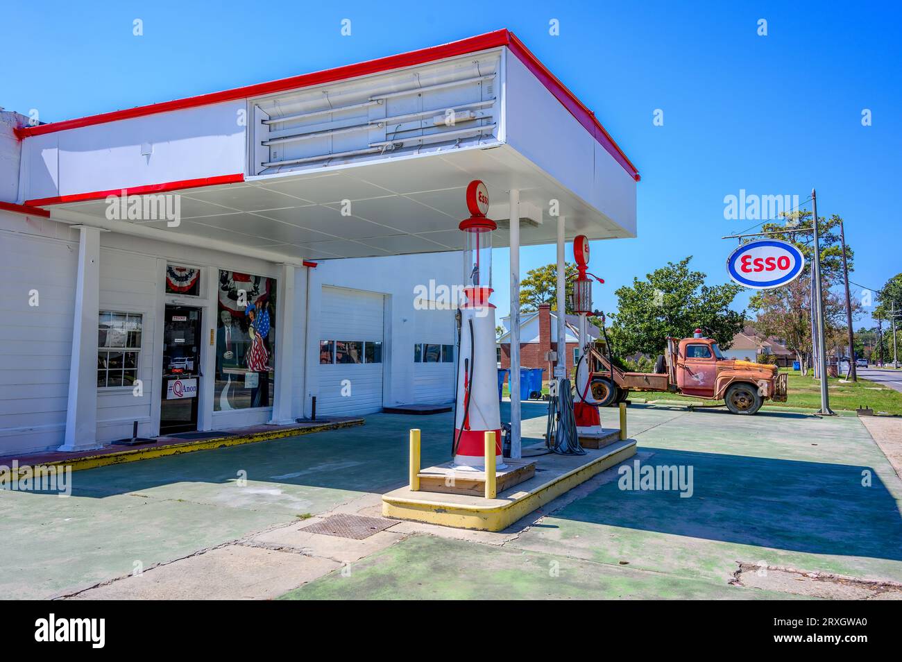NEW ROADS, LA, USA - 19. SEPTEMBER 2023: Retro Esso Tankstelle mit politischen Schildern, antiken Pumpen und einem rostigen Vintage-Abschleppwagen Stockfoto