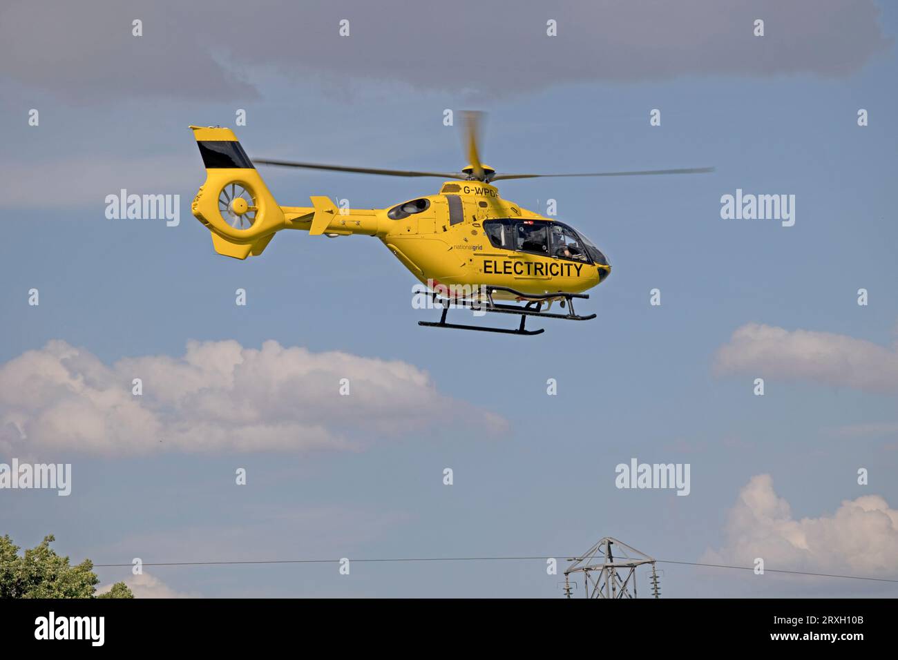 Hellgelber National Grid Elektrizitätshubschrauber im Flug, der Hochspannungsleitungen in der Nähe von Mickleton Chipping Campden UK überprüft Stockfoto