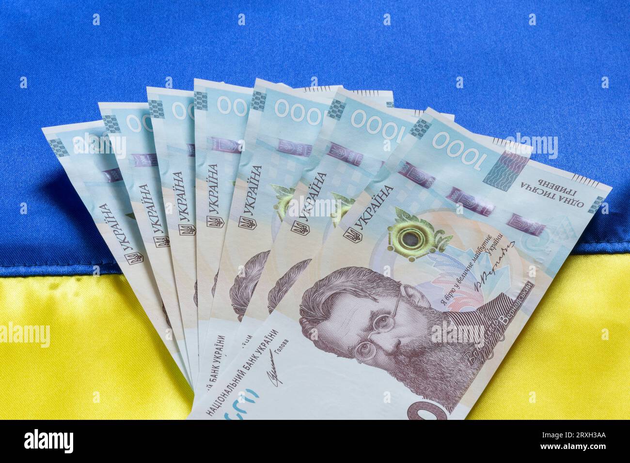 Mehrere tausend ukrainische Hrivnya-Banknoten liegen auf ukrainischer Flagge Stockfoto