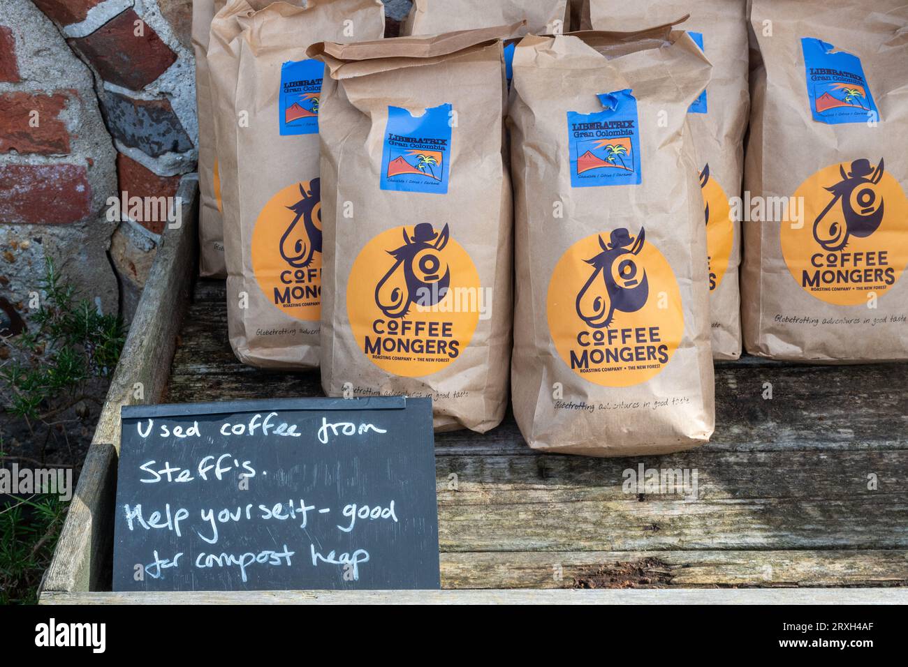 Beutel mit gebrauchtem Kaffeesatz zum Nehmen, mit Schild mit der Aufschrift „gut für Komposthaufen“ Stockfoto