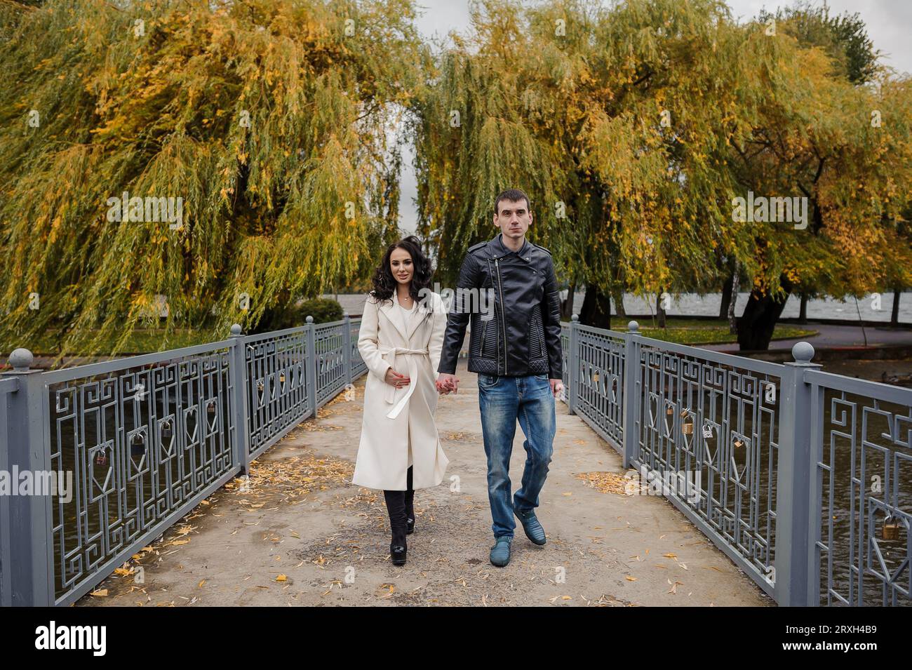 Ein Mann geht mit seiner schwangeren Frau im Park spazieren Stockfoto