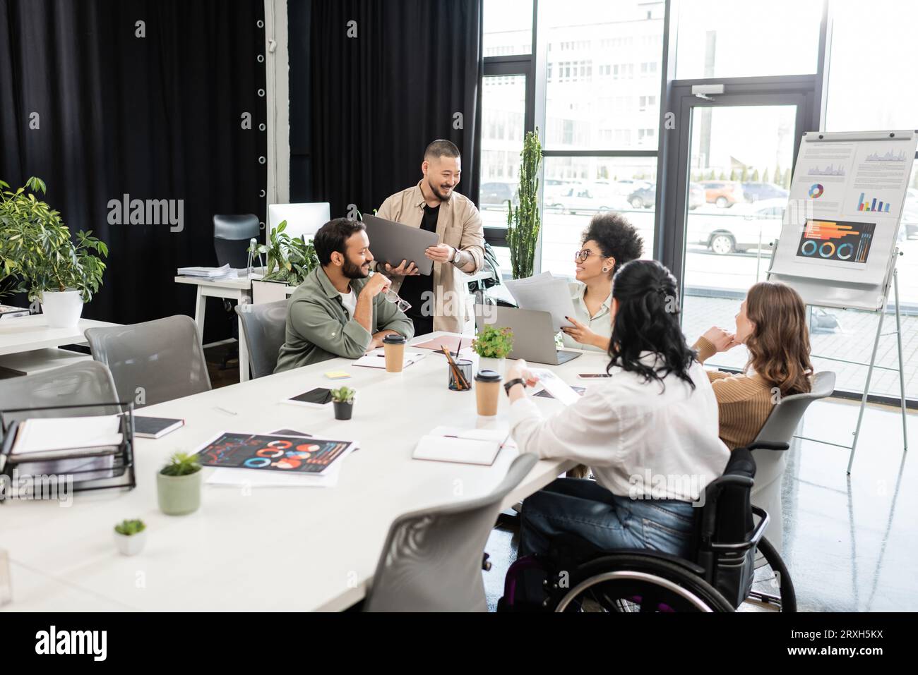 Interrassisches Startup-Team, das Projekt diskutiert und Ideen teilt, Geschäftsfrau im Rollstuhl Stockfoto