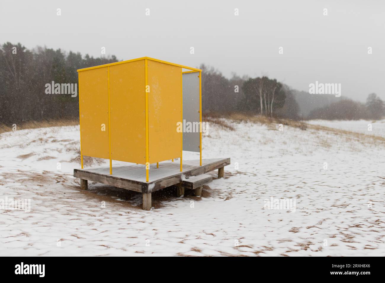 Gelber Strandumkleideraum auf Holzplattform im Winter. Stockfoto