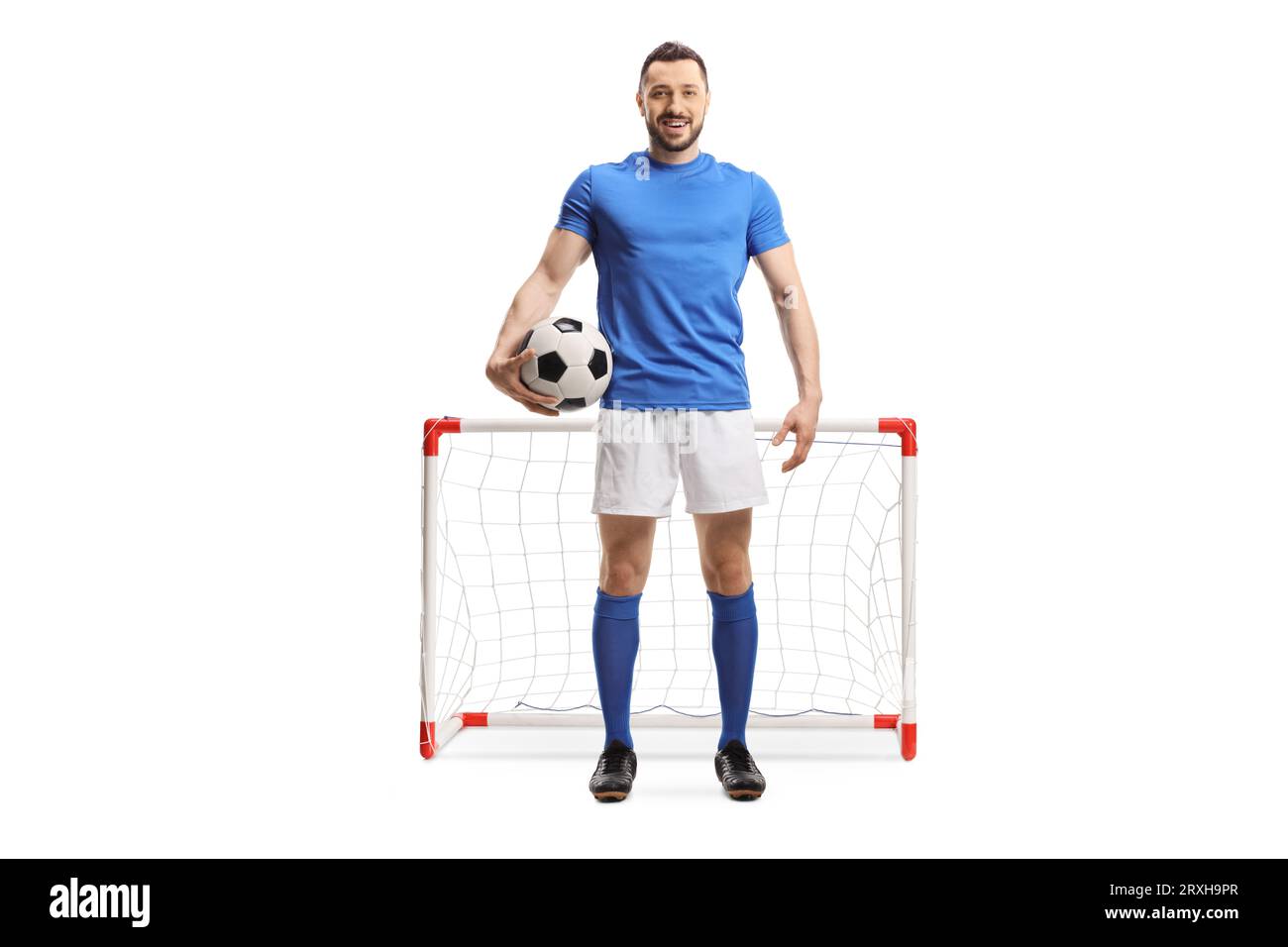 Portrait eines Fußballspielers, der einen Ball vor einem Minitor hält, isoliert auf weißem Hintergrund Stockfoto