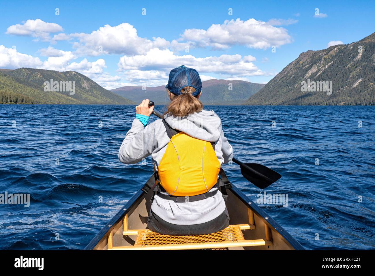 Frau, die ein Kanu auf einem abgelegenen Yukon See paddelt, mit wunderschöner Landschaft um sie herum; Yukon, Kanada Stockfoto