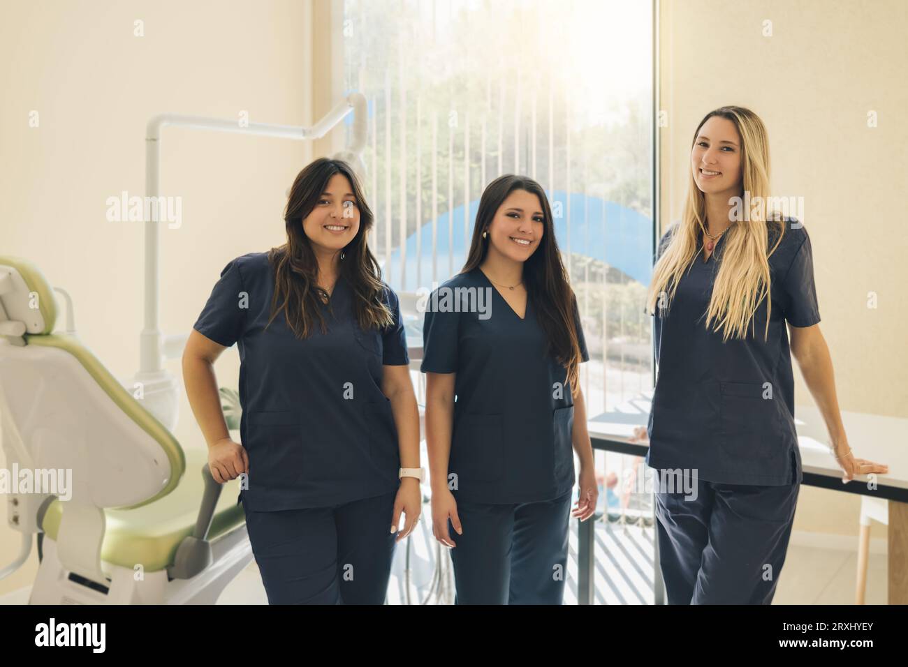 Das Konzept der Zahnheilkunde. Zahnärztliche Leistungen. Ein Team von Fachleuten in einer Zahnklinik. Drei schöne Zahnärztinnen lächeln und sehen sich die Kamera im Zahnarzt an Stockfoto