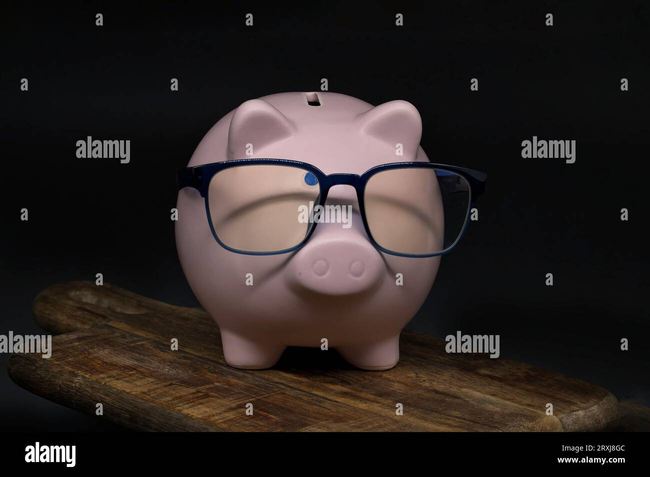 Eine Schweinebank aus Keramik, die ein Paar Gläser trägt, fast so, als wäre es ein gelehrtes Schwein, das sich darauf vorbereitet, einige Zahlen zu knacken. Hintergrund ist schwarz und fügt ein SENSE o hinzu Stockfoto