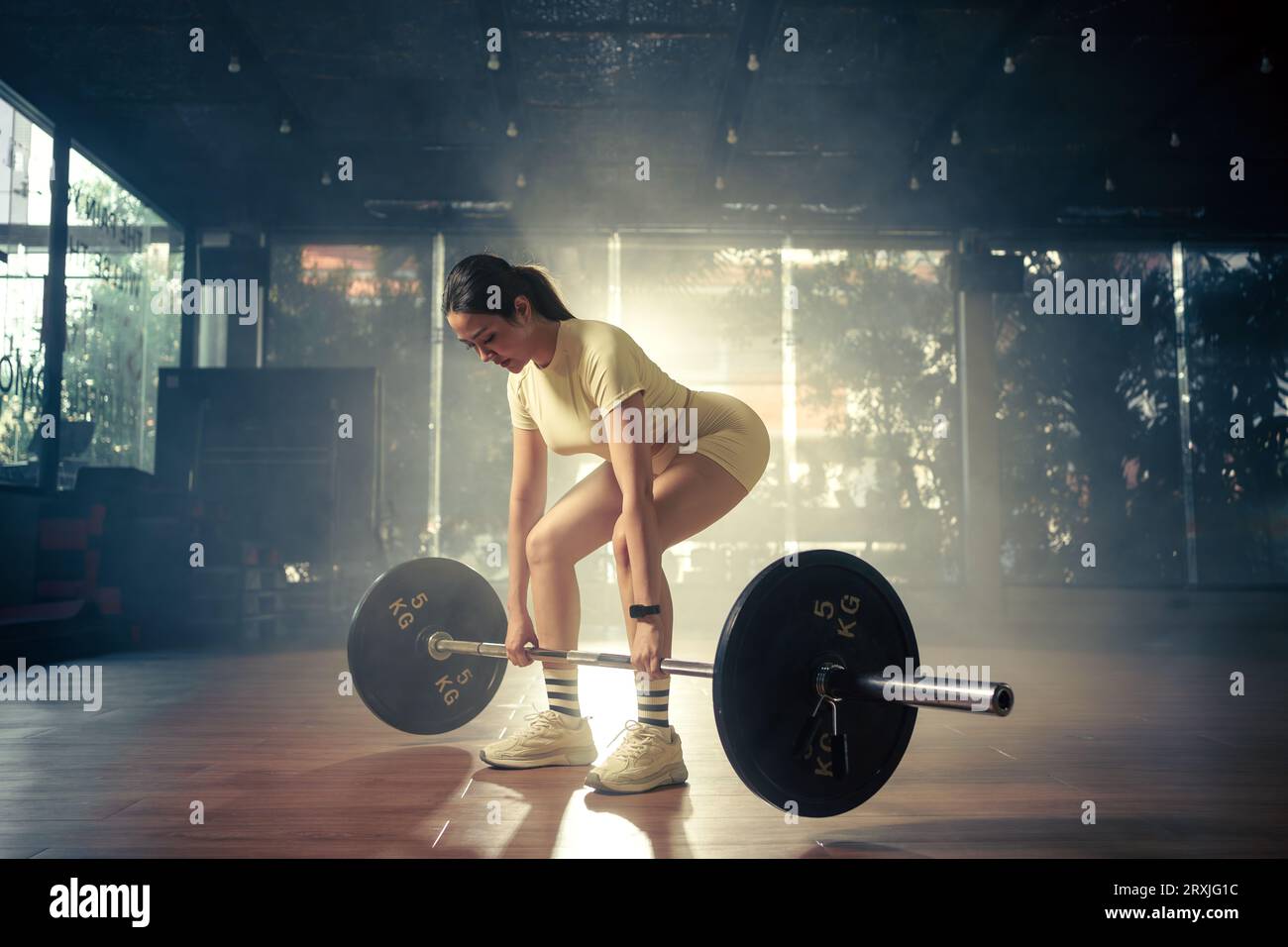 Junge Frau, die Deadlift mit schwerer Stange im Fitnessstudio macht, starke Sportlerin mit muskulösen Körpergewichten, die mit Langhantel trainiert. Stockfoto