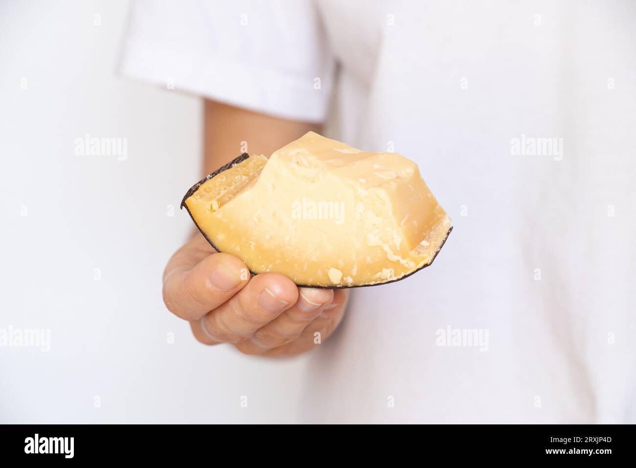 Ein Mädchen hält ein Stück Hartkäse in der Hand auf einem weißen Hintergrund Stockfoto