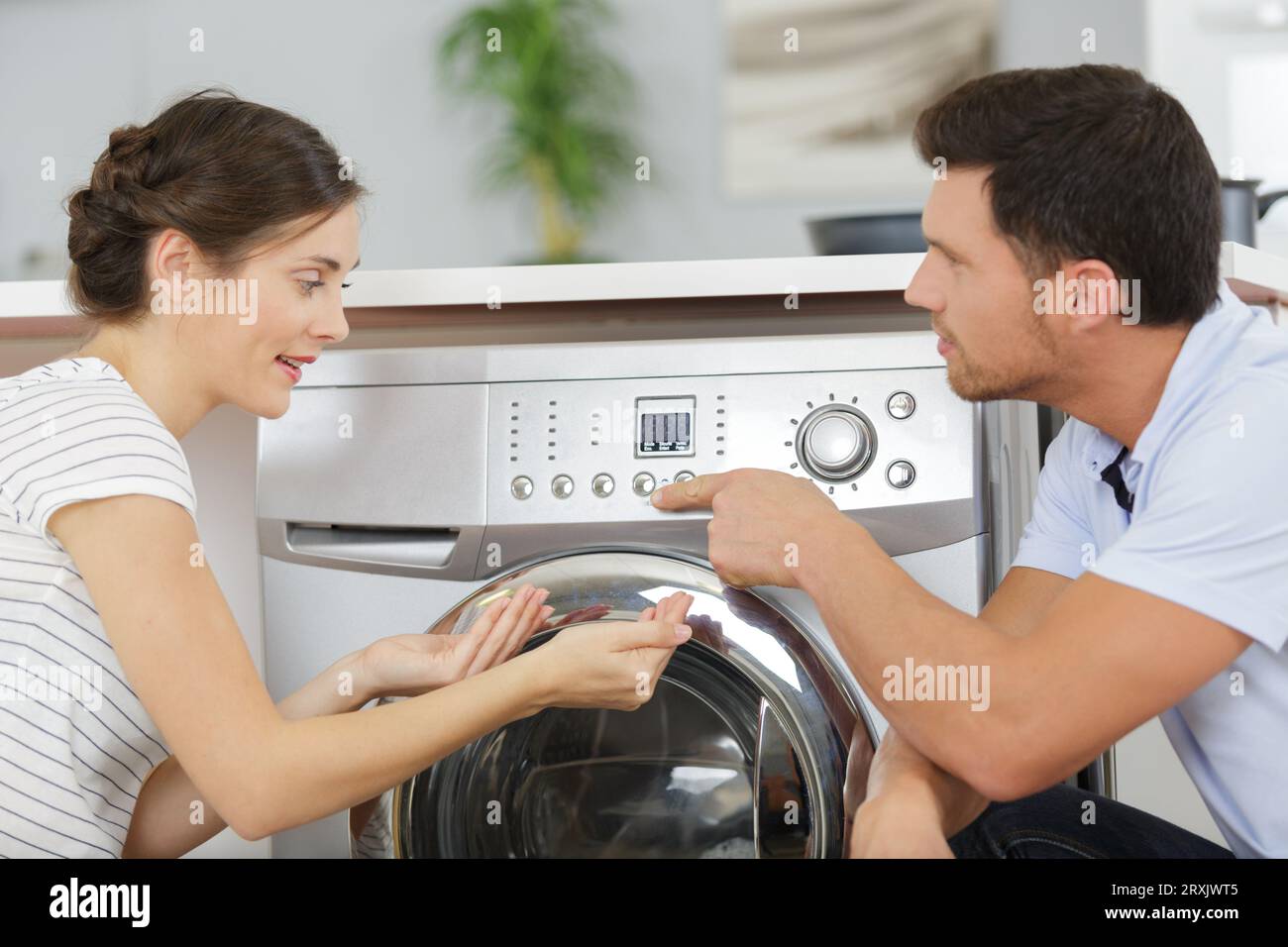 Ein Paar schaut sich die Waschmaschine an Stockfoto