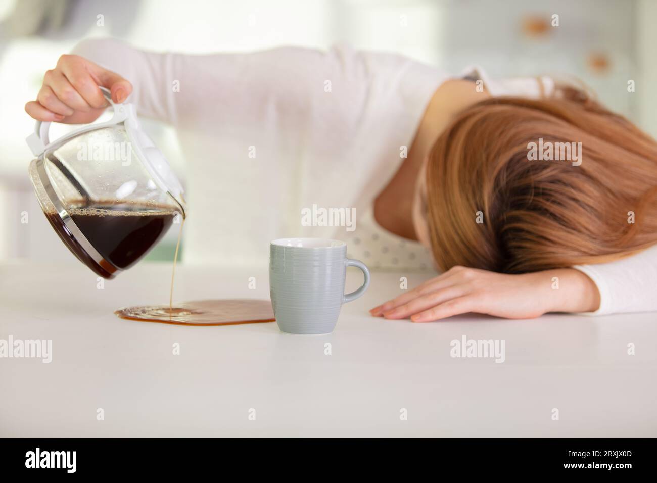 Müde Mutter, die versucht, am Morgen Kaffee zu gießen Stockfoto
