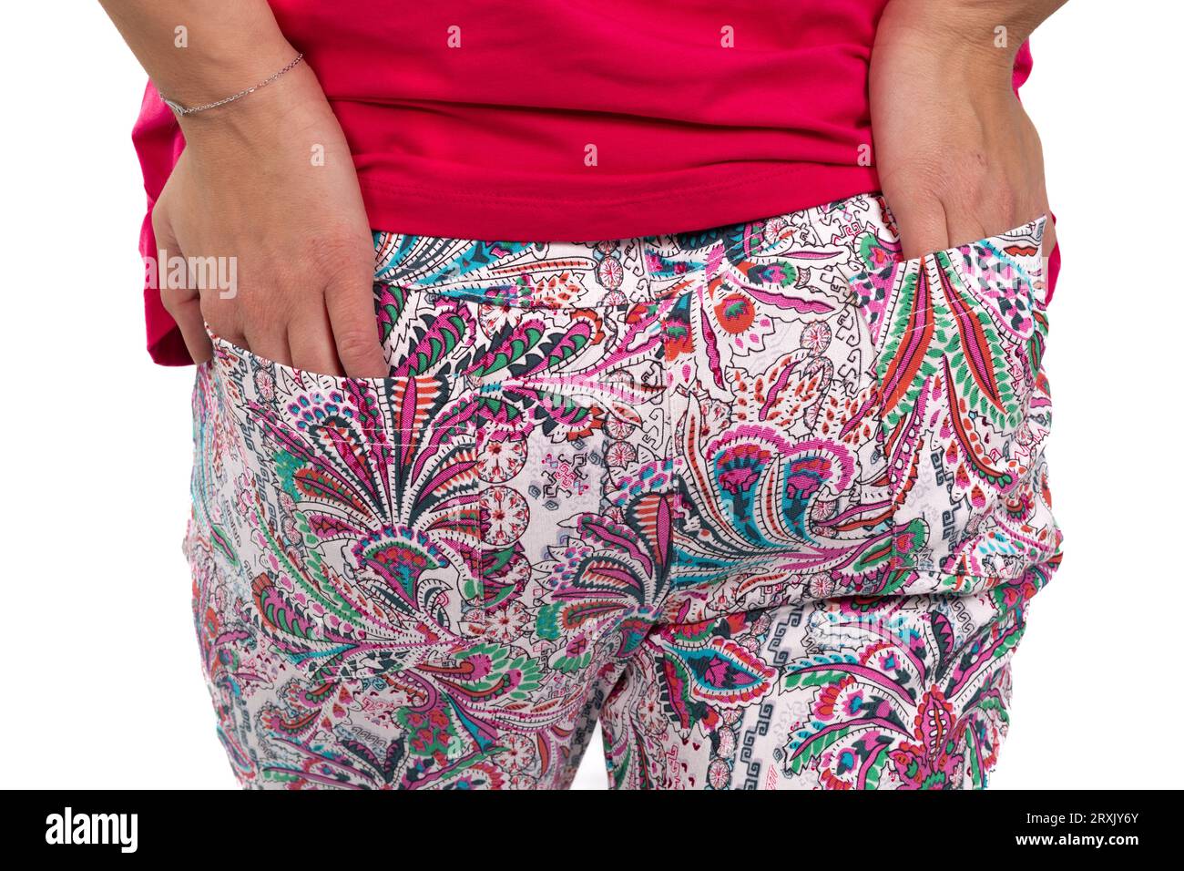 Ein Nahaufnahme-Bild zeigt die Hände einer Frau, die bequem in den hinteren Taschen ihrer farbenfrohen Hose mit Muster verstaut ist Stockfoto