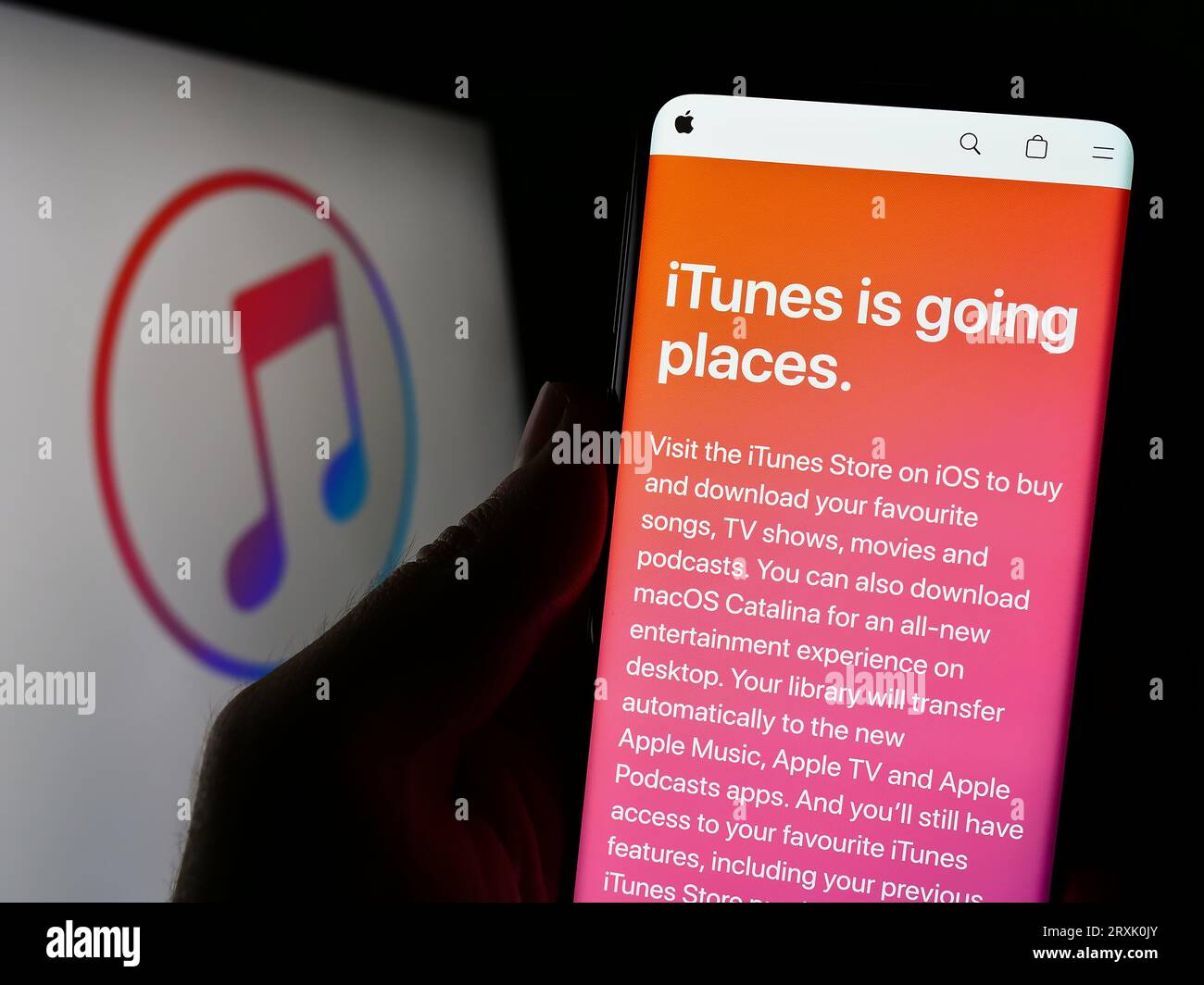 Person, die ein Mobiltelefon mit einer Webseite des Mediensoftwareprogramms Apple iTunes auf dem Bildschirm vor dem Logo hält. Konzentrieren Sie sich auf die Mitte der Telefonanzeige. Stockfoto