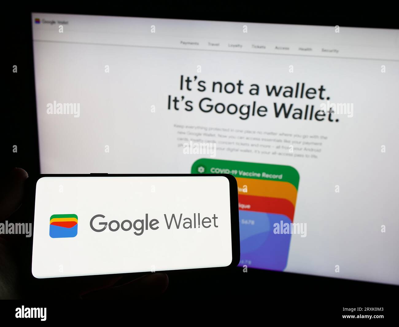 Person, die ein Mobiltelefon mit dem Logo der digitalen Wallet-Anwendung Google Wallet auf dem Bildschirm vor der Firmenwebsite hält. Konzentrieren Sie sich auf das Display des Telefons. Stockfoto