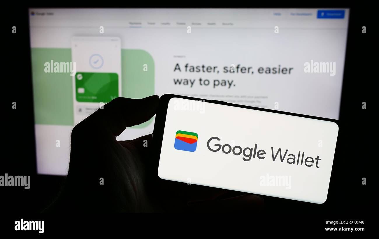 Person, die ein Smartphone mit dem Logo der digitalen Wallet-Anwendung Google Wallet auf dem Bildschirm vor der Website hält. Konzentrieren Sie sich auf das Display des Telefons. Stockfoto