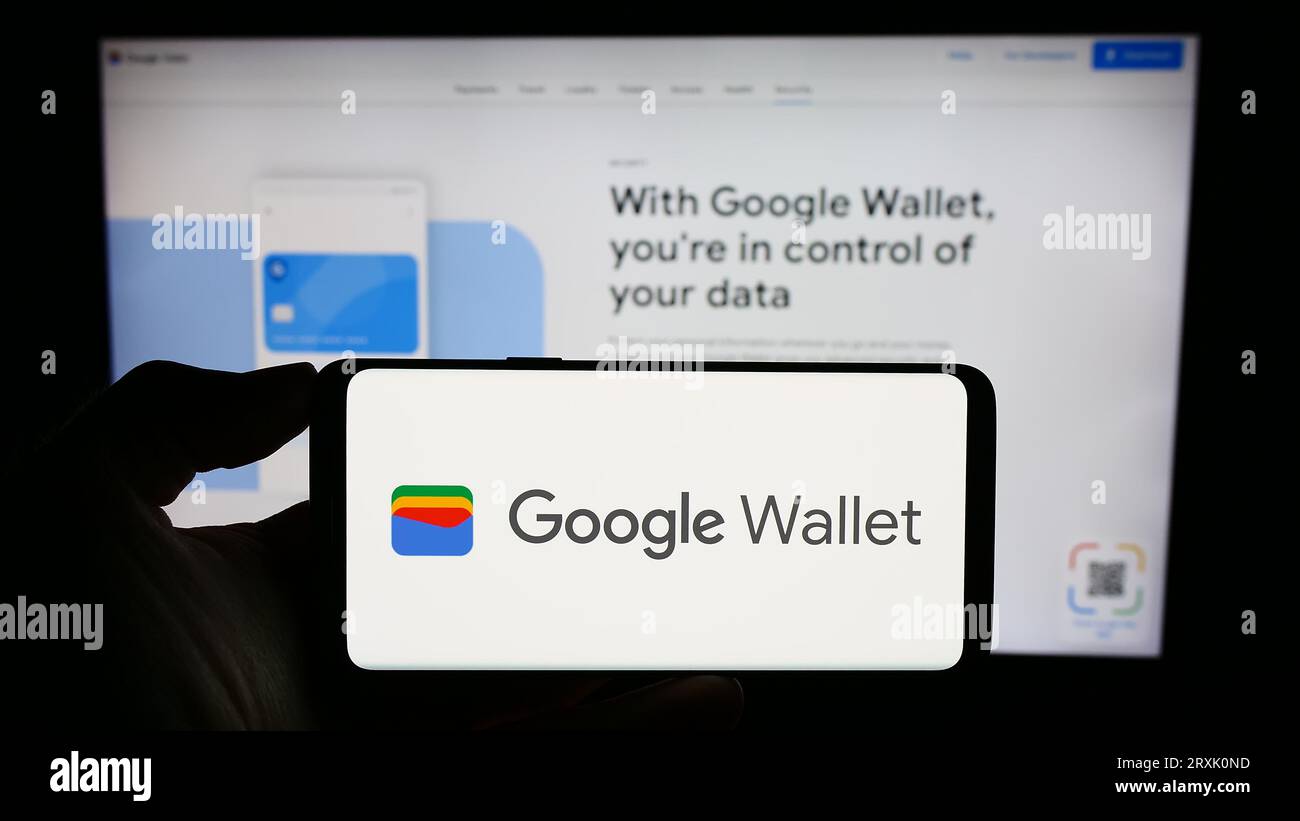 Person, die ein Mobiltelefon mit dem Logo der digitalen Wallet-Anwendung Google Wallet auf dem Bildschirm vor der geschäftlichen Webseite hält. Konzentrieren Sie sich auf das Display des Telefons. Stockfoto