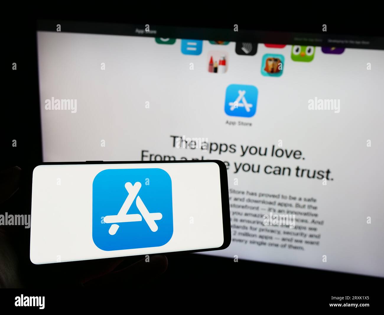 Person, die ein Mobiltelefon mit dem Logo der Marketplace-Plattform Apple App Store auf dem Bildschirm vor der Firmenwebsite hält. Konzentrieren Sie sich auf das Display des Telefons. Stockfoto