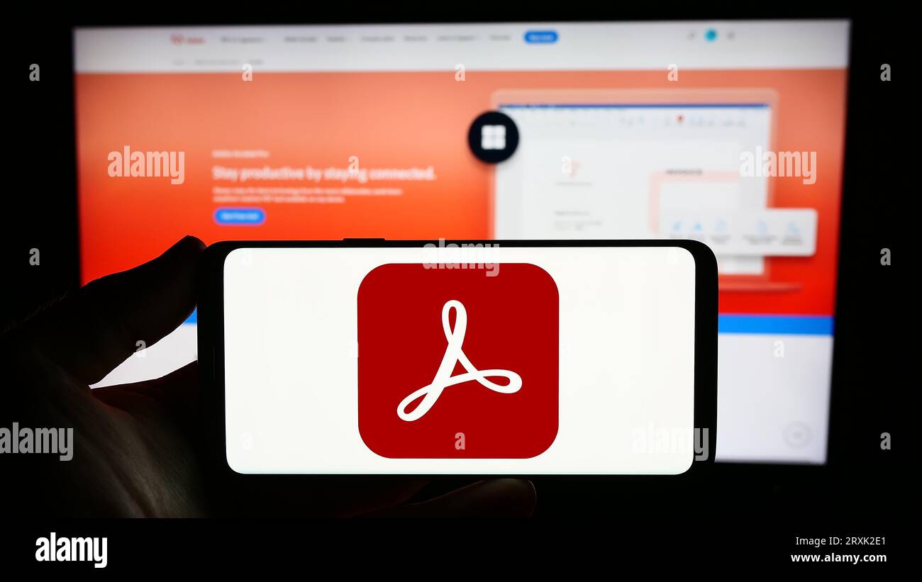 Person, die ein Smartphone mit dem Logo der PDF-Verwaltungssoftware Adobe Acrobat auf dem Bildschirm vor der Website hält. Konzentrieren Sie sich auf das Display des Telefons. Stockfoto