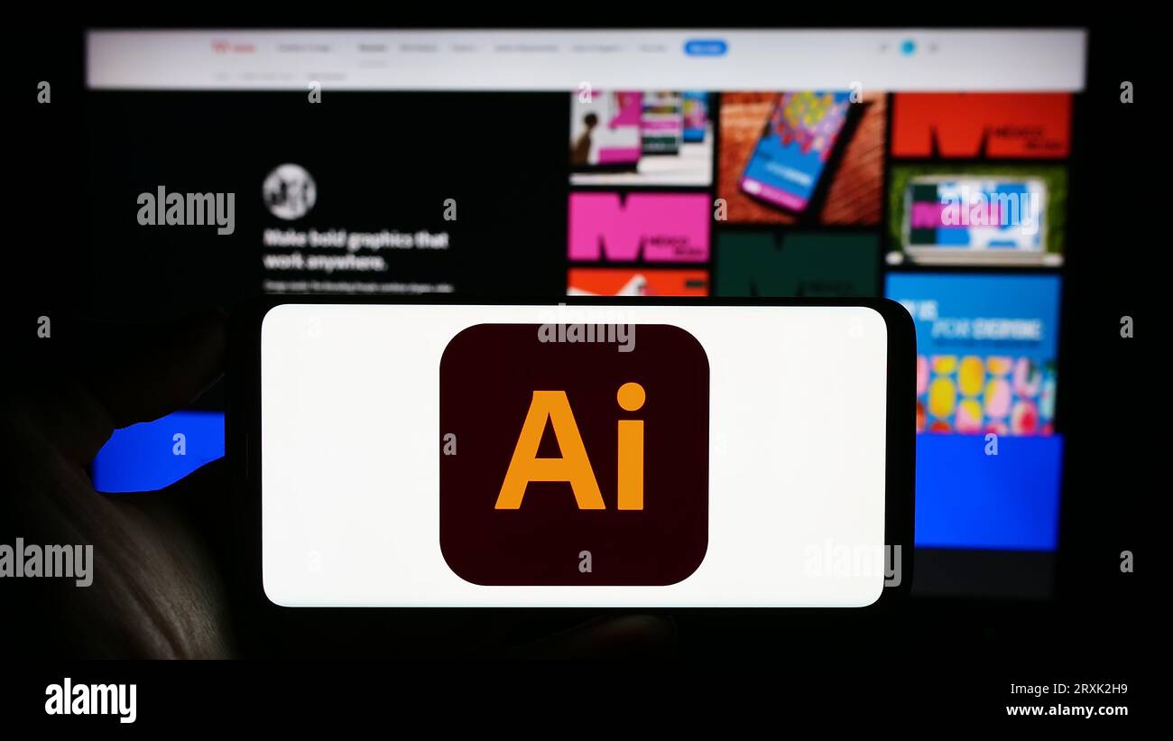 Person, die ein Mobiltelefon mit dem Logo des Vektorgrafik-Editors Adobe Illustrator auf dem Bildschirm vor der Firmenwebsite hält. Konzentrieren Sie sich auf das Display des Telefons. Stockfoto