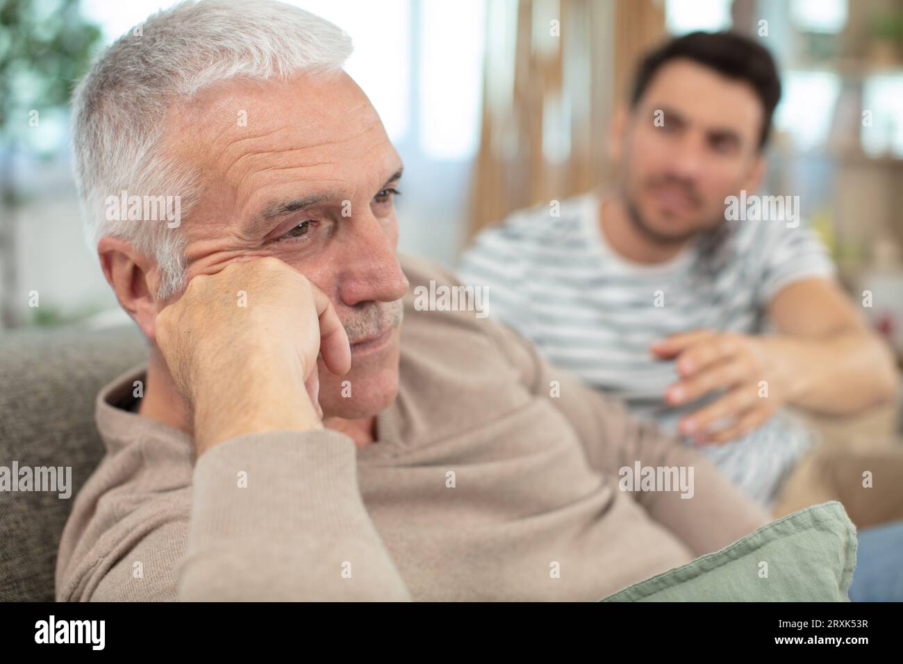 Sohn, der seinen Vater auf einem modernen Sofa beleidigt Stockfoto